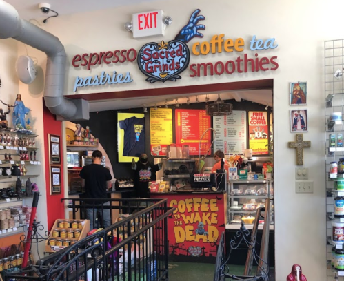 A colorful café entrance with signs for espresso, pastries, coffee, tea, and smoothies, featuring a vibrant interior.