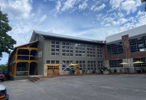 A large building with a mix of modern and rustic architecture, featuring large windows and a wooden porch.