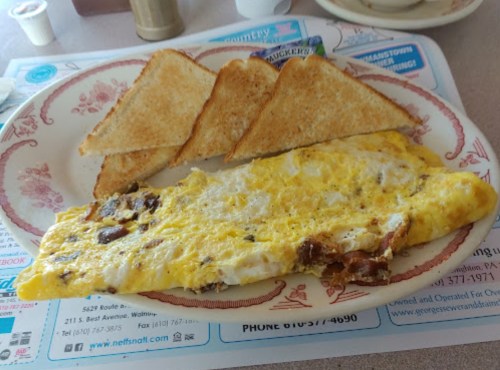 A plate with a fluffy omelet and three slices of toasted bread on a floral-patterned dish.