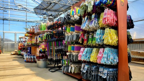 A greenhouse display featuring colorful gardening gloves, tools, and supplies neatly arranged on shelves.
