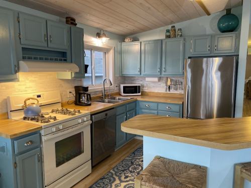 Bright kitchen with blue cabinets, stainless steel appliances, and wooden countertops, featuring a cozy, inviting atmosphere.
