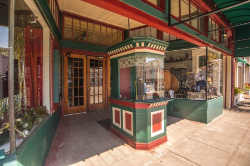 A colorful storefront with a decorative entrance and large windows showcasing various items inside.