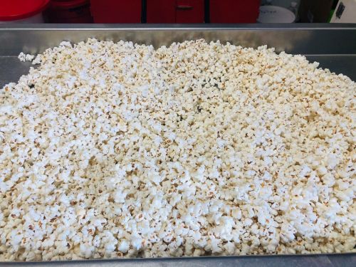 A large tray filled with freshly popped popcorn, with a light golden color and fluffy texture.