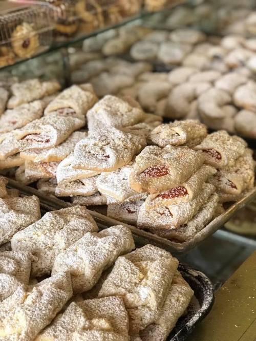 A display of assorted pastries dusted with powdered sugar, featuring some filled with jam.