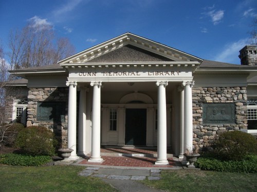 Front view of Cunn Memorial Library, featuring stone architecture and white columns under a clear blue sky.