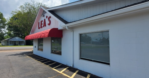 Exterior of Lea's restaurant with a red awning, featuring large windows and a clear blue sky in the background.