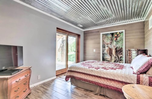 Cozy bedroom with a quilted bed, wooden furniture, and a deer-themed wall art, featuring a door to the outdoors.