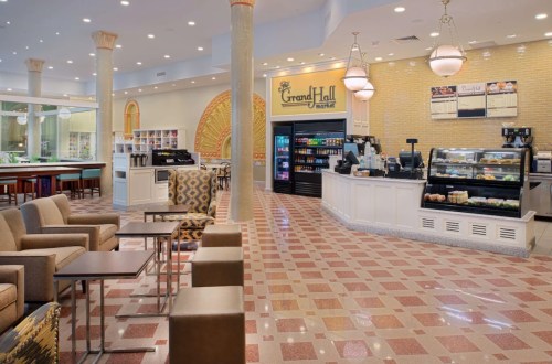 Bright, modern café interior with seating, a coffee counter, and a display of snacks and beverages.