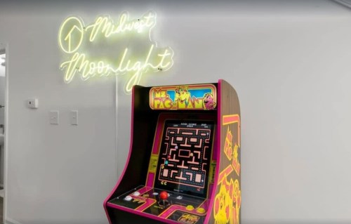A colorful Ms. Pac-Man arcade machine next to a neon sign that reads "Midwest Moonlight."