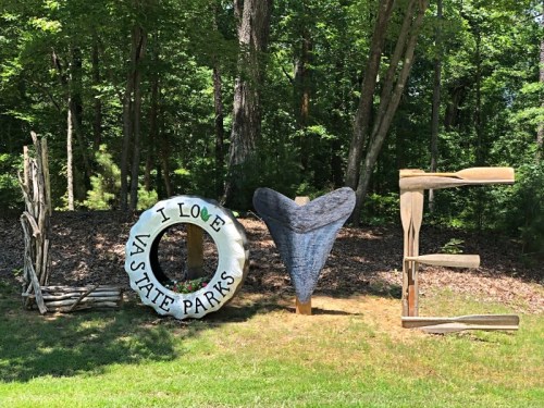 Wooden letters spelling "LOVE" with a heart and a sign that says "I LOVE VA STATE PARKS" in a forested area.