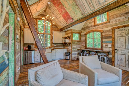 Cozy interior of a rustic cabin featuring wooden walls, a kitchen area, and comfortable seating.