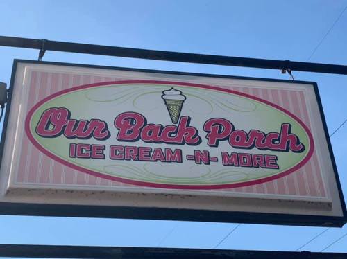 Sign for "Our Back Porch Ice Cream -N- More" featuring an ice cream cone graphic against a pastel background.