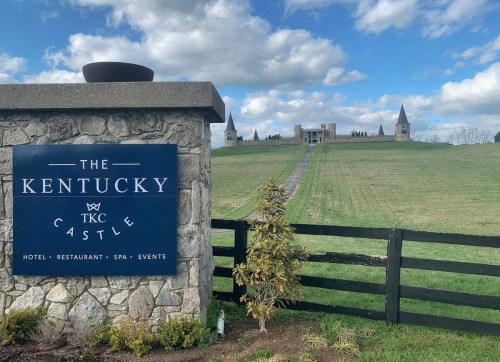 Sign for The Kentucky Castle, with a view of the castle in the background and a clear blue sky.