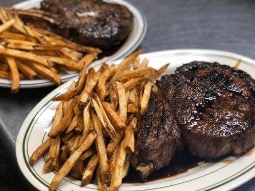 Two plates of juicy steak served with golden, crispy French fries.