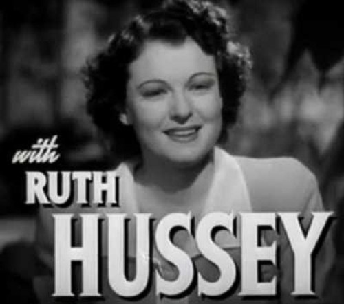 A smiling woman with curly hair, captioned "with RUTH HUSSEY," set against a blurred background.