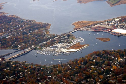 Aerial view of a marina surrounded by autumn foliage, with boats docked and a river winding through the landscape.