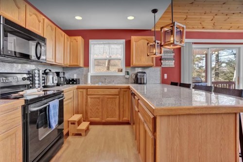 A modern kitchen with wooden cabinets, granite countertops, and stainless steel appliances, featuring a cozy dining area.