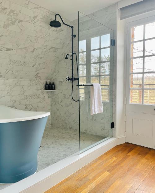 Modern bathroom featuring a glass shower, freestanding tub, and large windows with natural light.