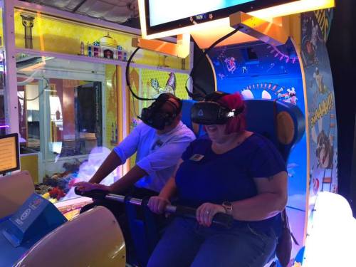 Two people wearing VR headsets sit in an arcade game, focused and enjoying the immersive experience.