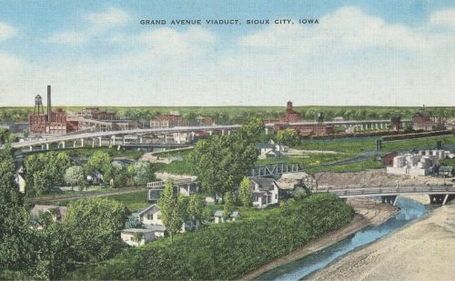 Vintage postcard of Grand Avenue Viaduct in Sioux City, Iowa, showcasing a river, buildings, and lush greenery.