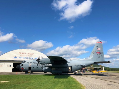 A U.S. Air Force C-130 aircraft parked at Drake Field, Fayetteville Air Museum, under a blue sky with clouds.