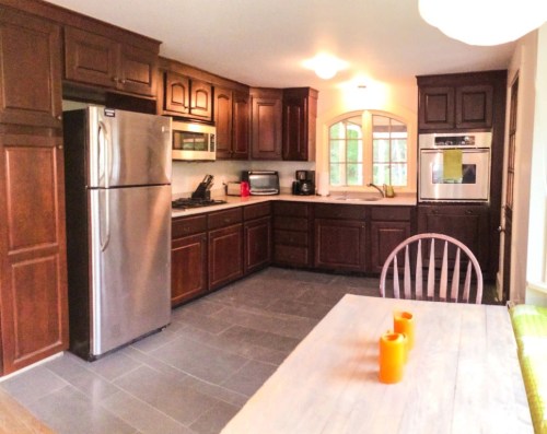 Modern kitchen with dark wood cabinets, stainless steel appliances, and a dining table with orange candles.