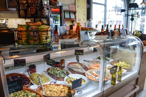 A display case filled with various colorful dishes, salads, and snacks in a cozy café setting.