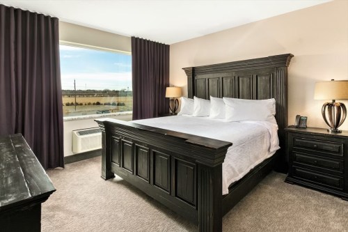 A cozy hotel room featuring a large bed, dark wood furniture, and a window with a view of the outdoors.