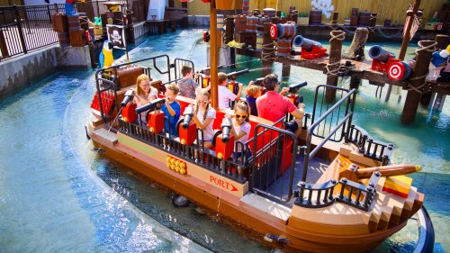 A colorful pirate-themed boat ride with children enjoying themselves on a water attraction.