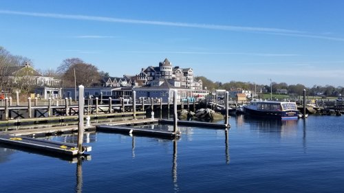 A serene waterfront scene with boats docked, a charming building in the background, and clear blue skies.