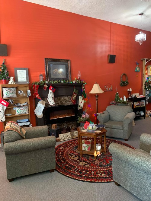 Cozy living room with orange walls, festive decorations, a fireplace, and two armchairs around a coffee table.
