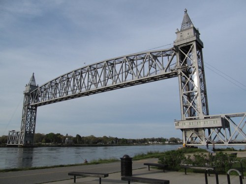 A large metal lift bridge spans a river, with towers on either side and a clear sky in the background.