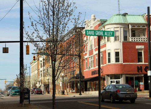 Street view featuring a sign for "David Grohl Alley" alongside historic buildings and blooming trees.