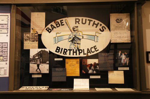 Exhibit display featuring Babe Ruth's birthplace, with photos, documents, and memorabilia related to his early life.