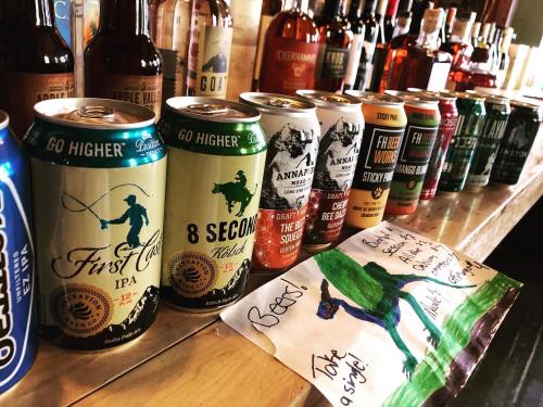A variety of beer cans lined up on a bar, with colorful drawings and labels in the foreground.