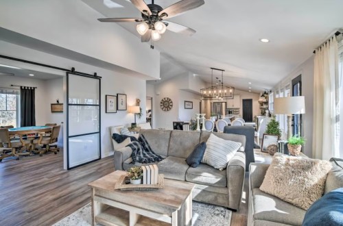 Cozy living room with a beige sofa, wooden coffee table, and open layout leading to a dining area and game room.