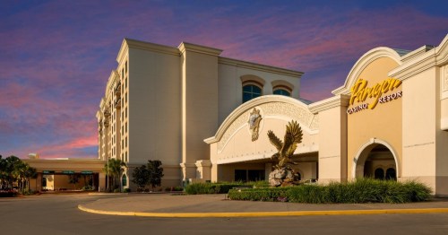 Exterior view of a casino resort at sunset, featuring a large eagle statue and elegant architecture.