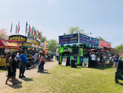 A vibrant outdoor food festival with colorful stalls, flags, and crowds enjoying various food and drinks.