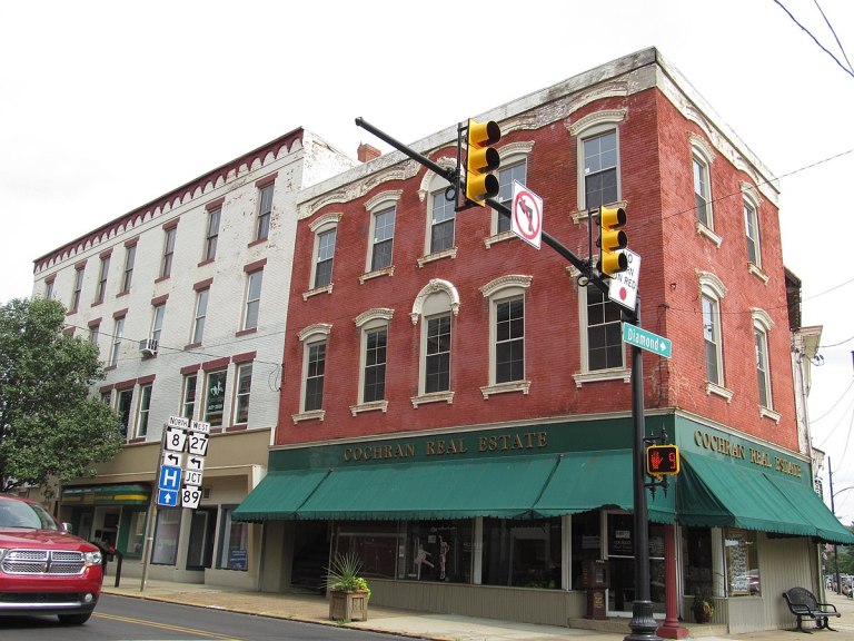 Historic brick buildings with storefronts, including Cochran Real Estate, at a street intersection with traffic lights.