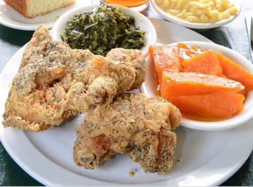 A plate of fried chicken, collard greens, sweet potatoes, macaroni and cheese, and cornbread.