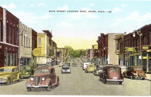 Vintage postcard of Main Street in Niles, Michigan, featuring classic cars and storefronts along a bustling street.