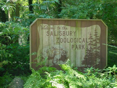 Sign welcoming visitors to Salisbury Zoological Park, surrounded by lush greenery and trees.