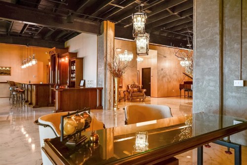 Elegant interior featuring a bar, piano, and stylish seating with decorative lighting and marble flooring.
