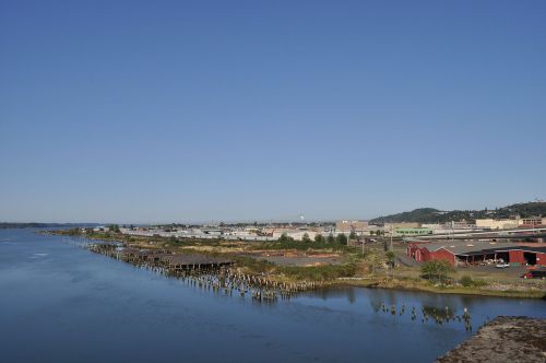 A panoramic view of a riverfront industrial area with buildings, docks, and clear blue skies.