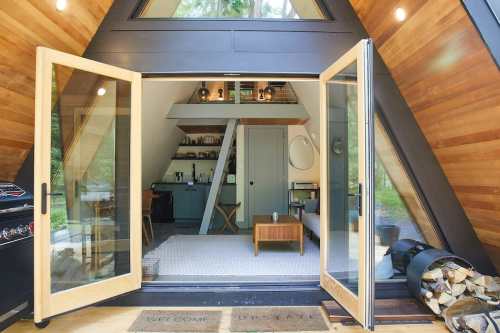 A cozy A-frame cabin interior with open doors, wooden accents, and a welcoming atmosphere.