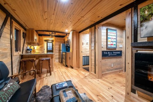 Cozy interior of a wooden tiny home featuring a kitchen, living area, and rustic decor with warm lighting.