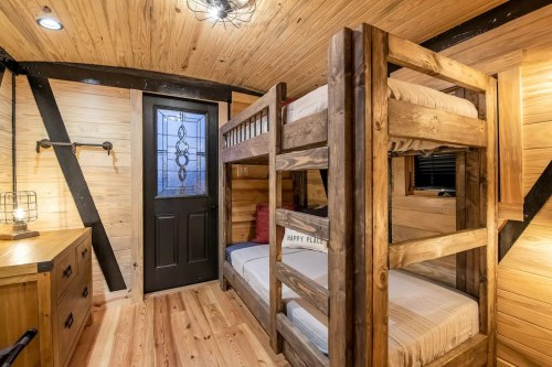 Cozy interior of a small room featuring a bunk bed, wooden furniture, and a door with decorative glass.