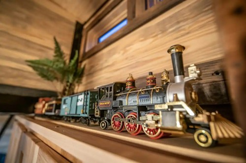 A detailed model train displayed on a wooden shelf, with a small plant in the background.