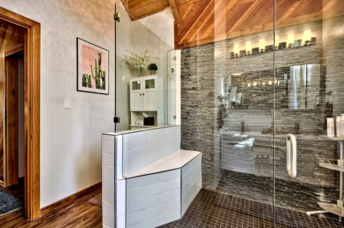Modern bathroom featuring a glass shower, bench seating, and stylish decor with wooden accents.