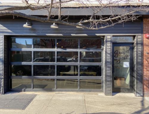 A modern storefront with large glass windows and a black exterior, featuring a sign that reads "Bread and Salt."